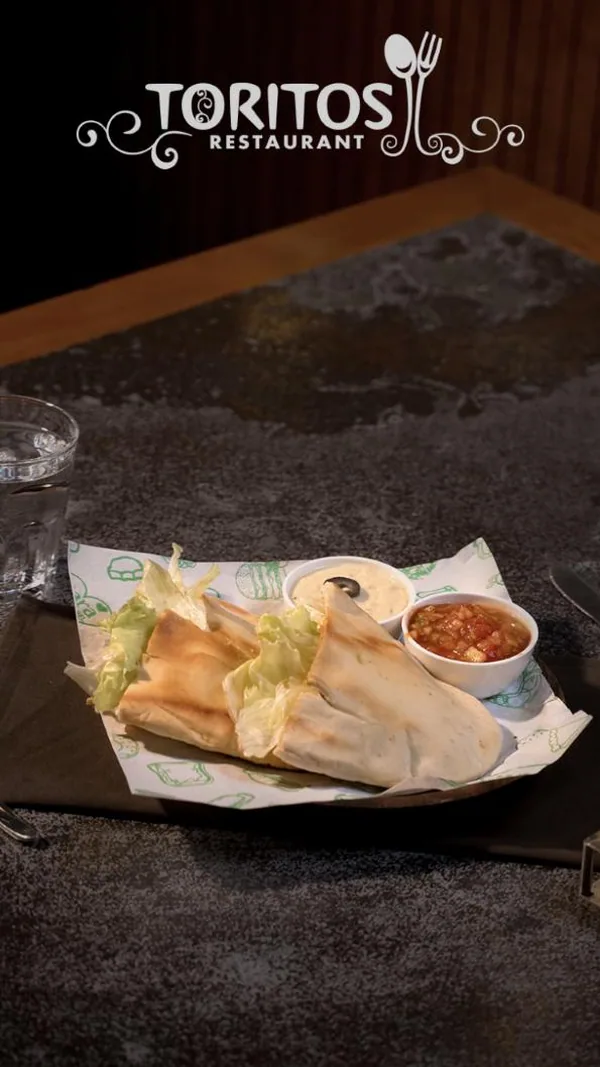 Dish post: falafel wraps and dips, shot moody on a stone table.